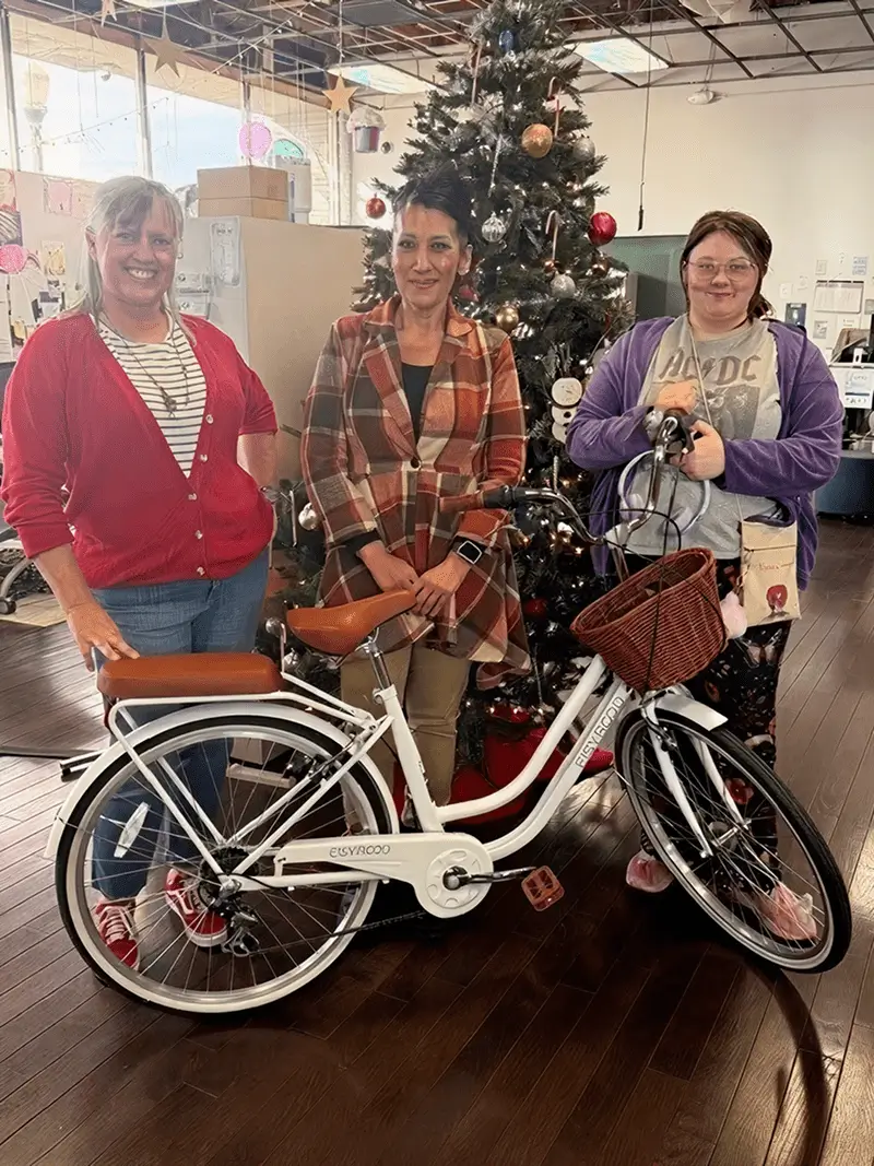 Three women posing with bicycle