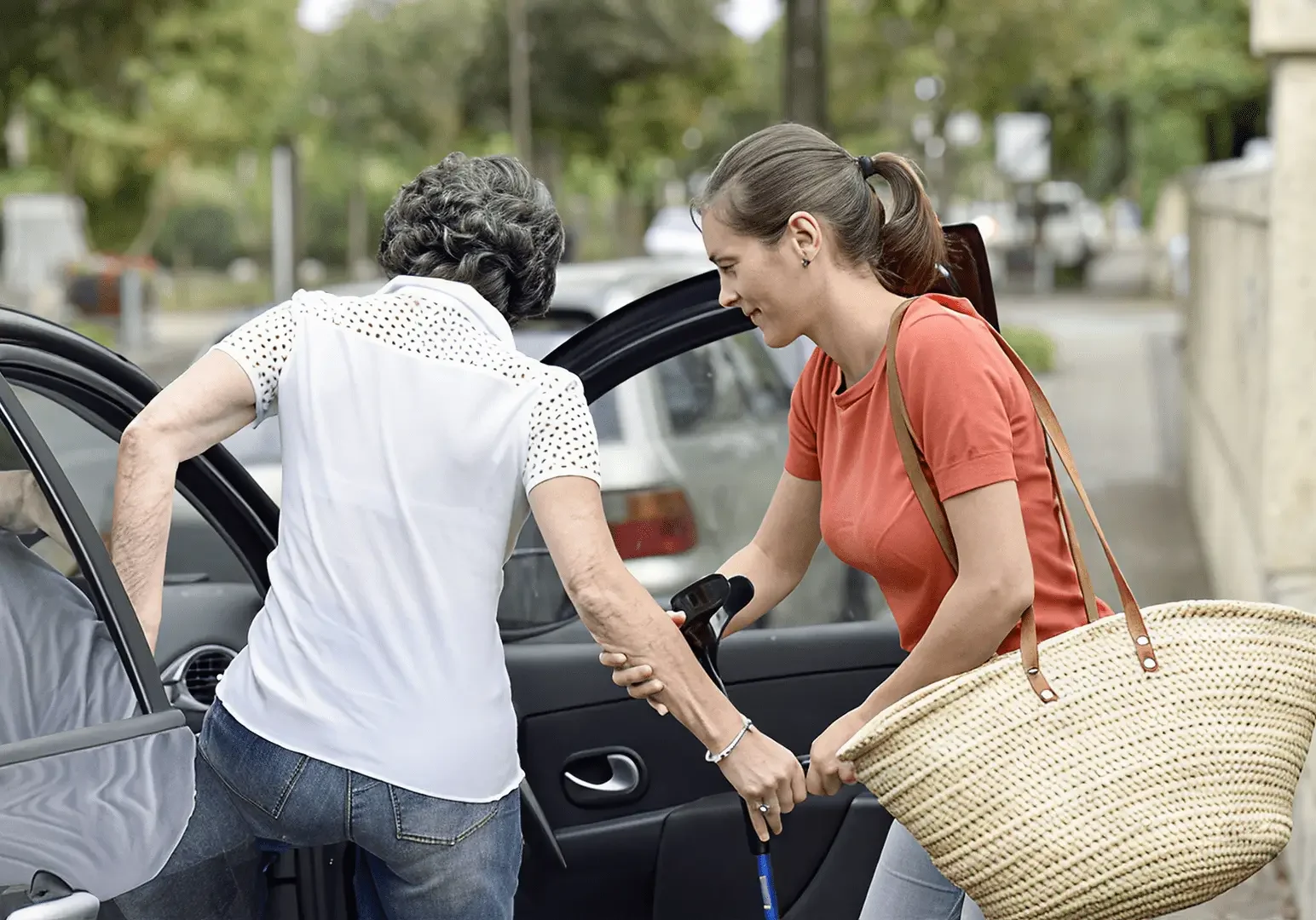 A young woman assisting elderly woman out of car